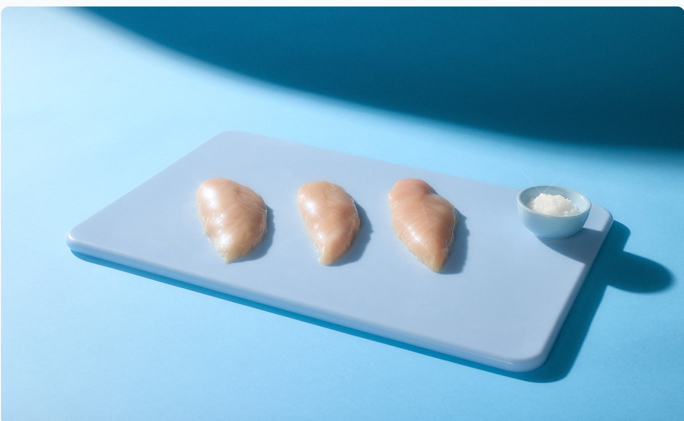 Three pieces of raw chicken in a cyan studio