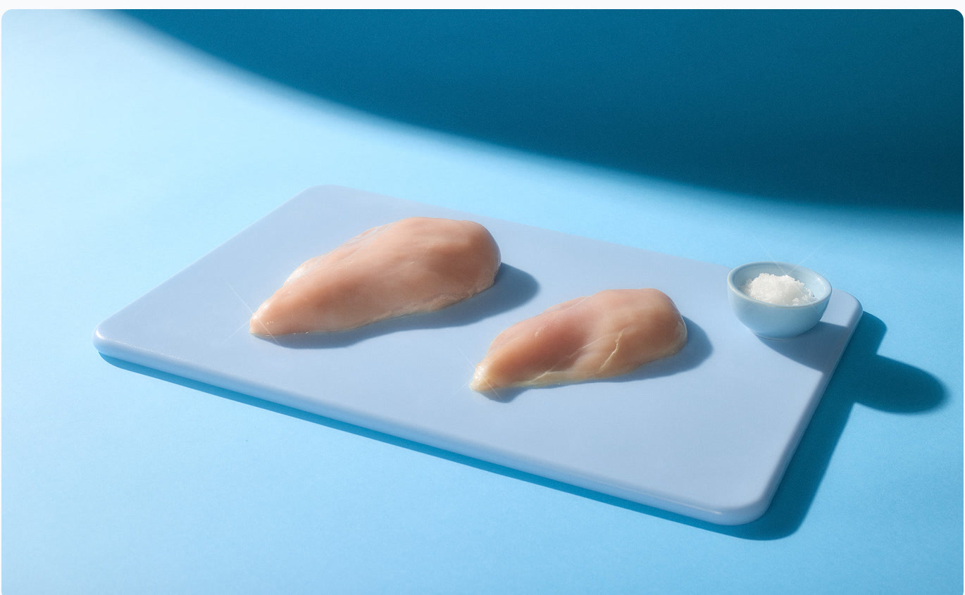 Raw chicken on a blue cutting board in a cyan studio